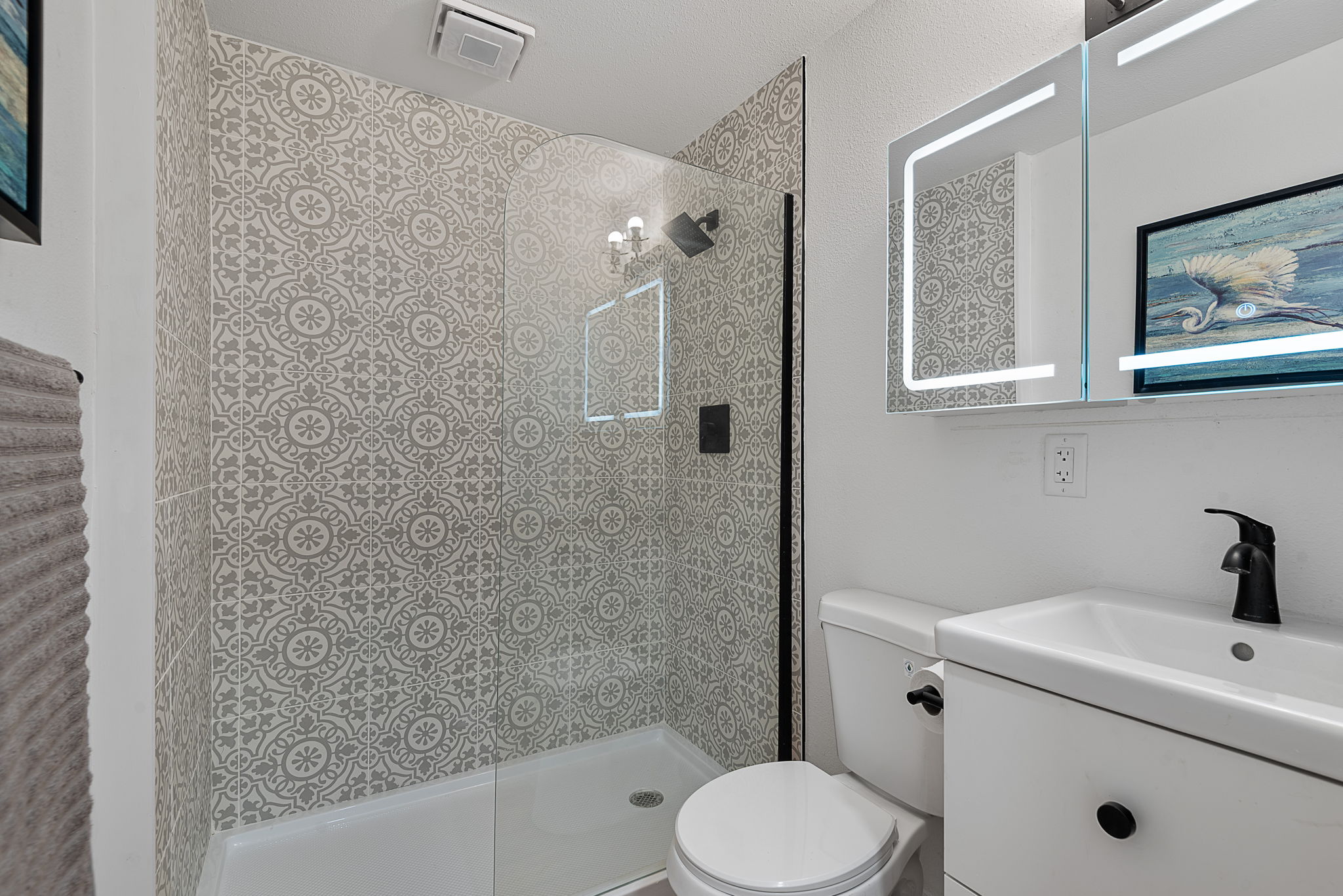 Full bath with walk-in tile shower and lighted mirror